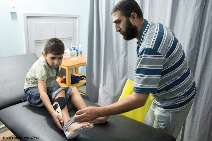 リハビリに訪れた父子。イスラエル軍の発砲で息子は膝を損傷、父親は親指を切断した