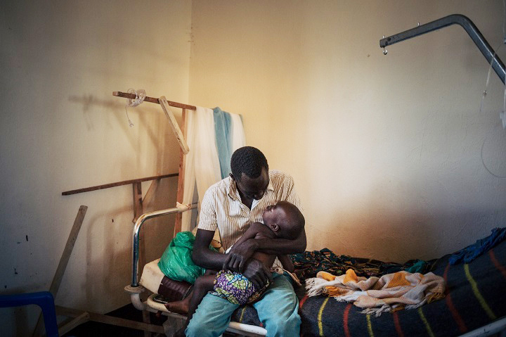 はしかにかかった2歳の娘を抱く父親（コンゴ）=2019年　© Alexis Huguet/MSF