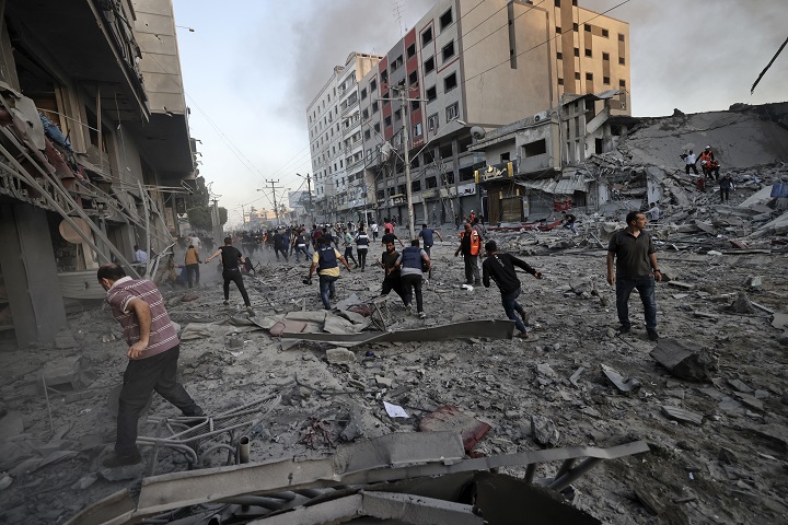 がれきの中を逃げ惑う人びと。多くの建物が空爆によって崩壊した　🄫 Mohammed ABED / AFP