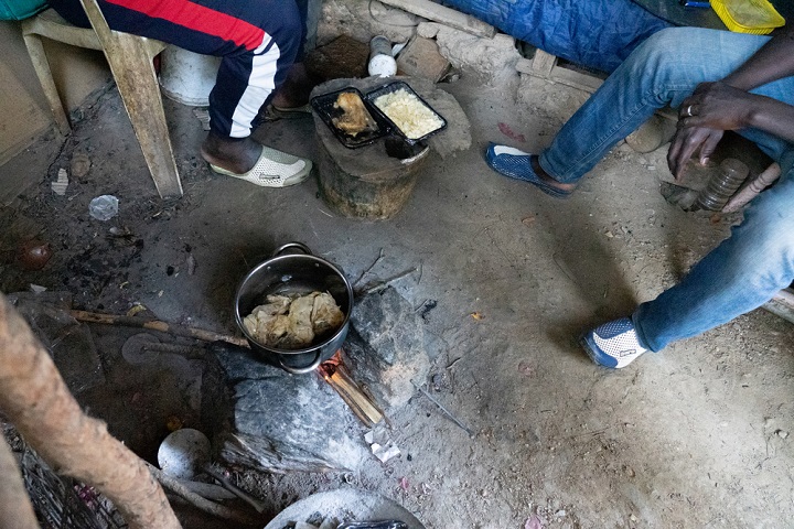 ホットスポットで配給された食事を温める男性たち　© Evgenia Chorou