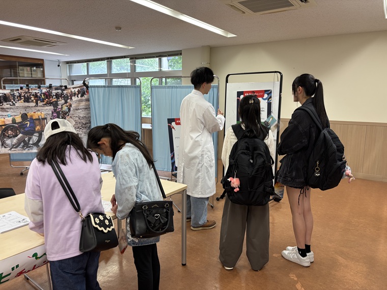 「熱帯・毒ヘビチャレンジ！」を来場者に説明する北海道大学の学生　© MSF