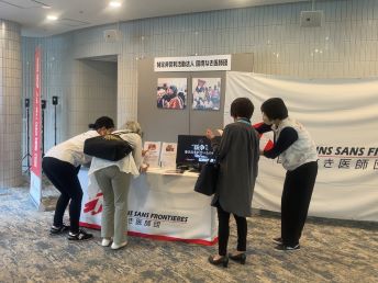 ブースで参加者に団体案内をするスタッフ 🄫 MSF
