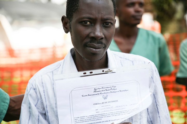 治癒証明書を手にエボラ治療センターを退院する男性患者© Carl Theunis/MSF