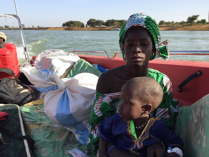 MSFによってボートで川を渡り、移動診療所に向かう親子。11人が殺された村から家族で逃げ出した　© Lamine Keita/MSF