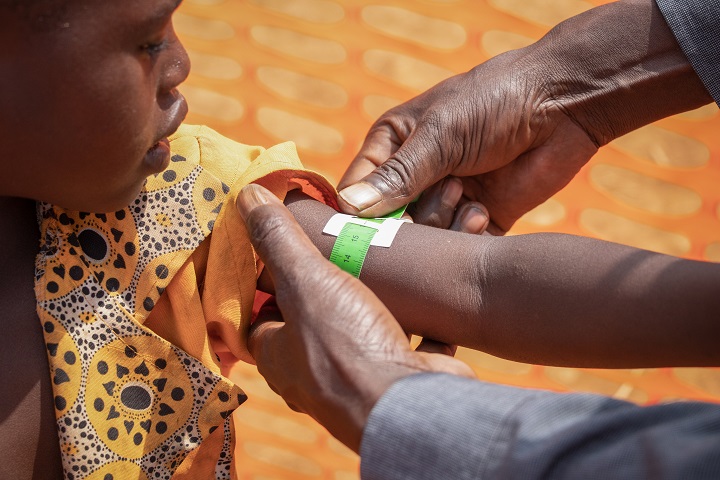 MSF現地スタッフが子どもの腕の太さを測り、栄養失調に陥っていないかを調べる様子　© Solen Mourlon/MSF