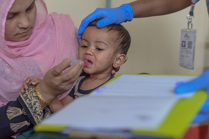 はしかに感染した2歳の息子に水を飲ませようとする母親　©Tariq Adnan/MSF