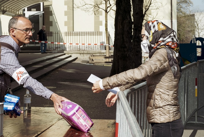 受け取る人との社会的距離を十分に取りながら、衛生用品などを配布するMSFスタッフ（左）<br>  © Nora Teylouni/MSF<br> 