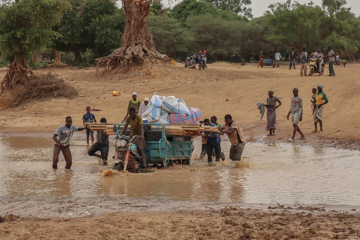 支援物資を運ぶ住民たち さらに雨が降ると渡ることができなくなる © Noelie Sawadogo/MSF