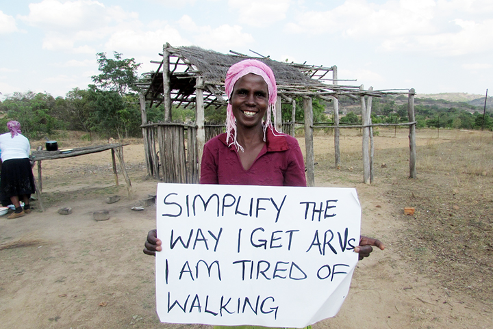 「HIV治療薬を得られやすくしてください。歩くのは疲れます」と書かれた紙を掲げるジンバブエ・グツ地区の患者女性　© Munyaradzi Makari/MSF