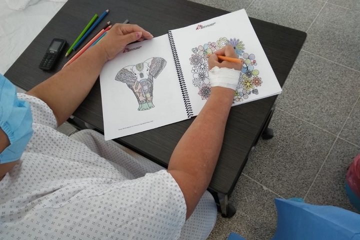 色とりどりの色鉛筆を使って塗り絵をする患者　このノートは入院時に手渡される　© MSF