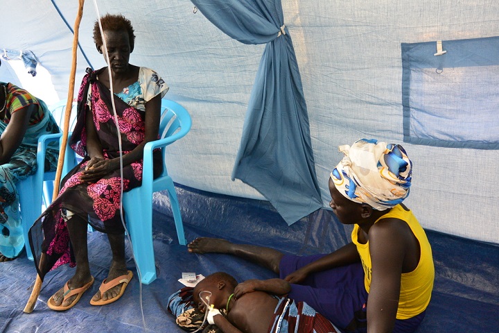 MSF移動診療所で重度マラリアを患う孫が安定するのを見守るウォルさん。一家はこの後、入院のため5時間歩いて民間病院へ向かった　© Damaris Giuliana/MSF