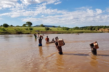 ラノベ地区へ向かうMSFのスタッフたち。ときには荷物を担いで川を渡ることも。　🄫 MSF