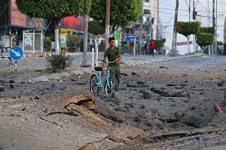 陥没した場所を避けながら自転車を押す男性<br> 🄫 MOHAMMED ABED / AFP