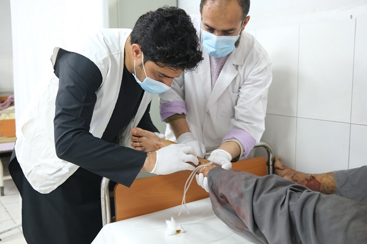 足に銃弾を受けた患者を治療するMSFの医師　🄫 MSF/Tom Casey