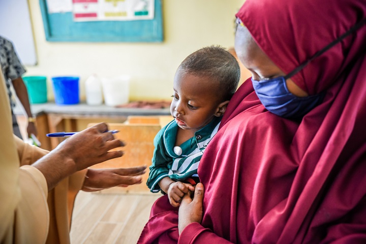 キャンプの診療所で子どもの診察を受ける難民の女性　© Paul Odongo/MSF