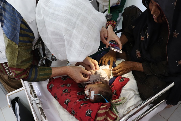 栄養失調の新生児を携帯電話のライトで診察するブースト病院の小児科医＝2019年4月　© MSF/Elise Moulin 