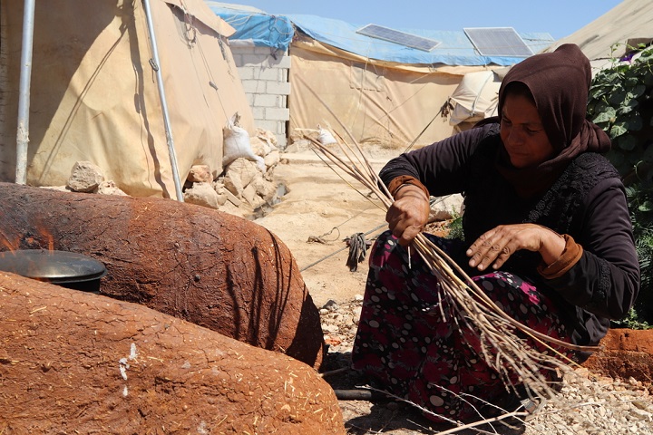 シリア北西部の避難民キャンプ。テントの外で薪をたいて調理する女性 © Abdurzaq Alshami