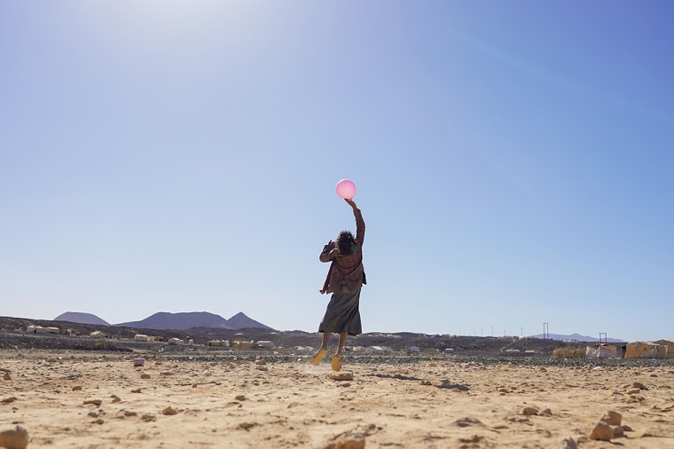 子ども向けの支援プログラムに参加し、風船で遊ぶ少女　　© Hesham Al Hilali