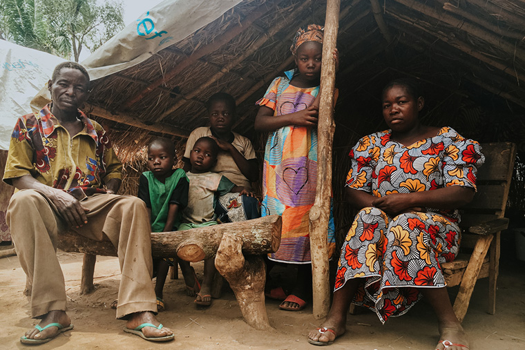 避難民キャンプのシェルター前に佇む、ジェレミィさんと妻のロジーヌさん、その子どもたち 　Ⓒ MSF