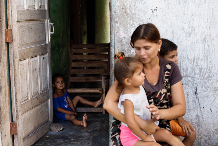 7人の子どものうち3人と一緒に、家の玄関に座るヘシカさん　Ⓒ Jesus Vargas