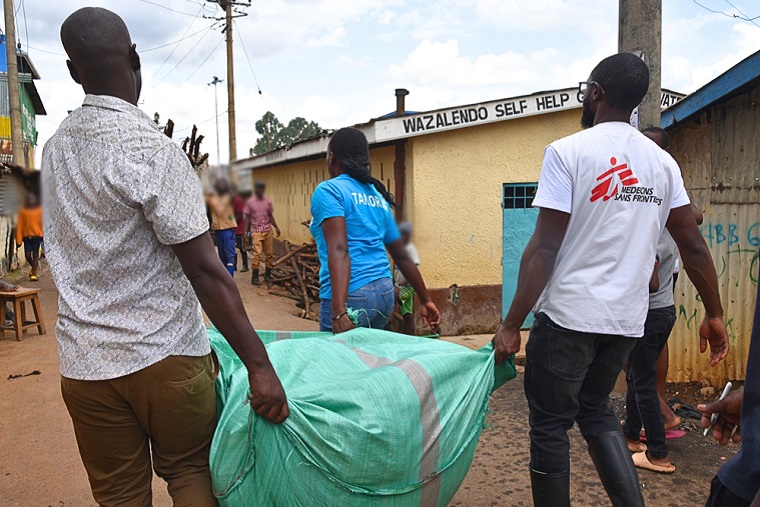 子どもたちに配布する衣類を地域住民と運ぶMSFのスタッフ　© MSF/Lucy Makori