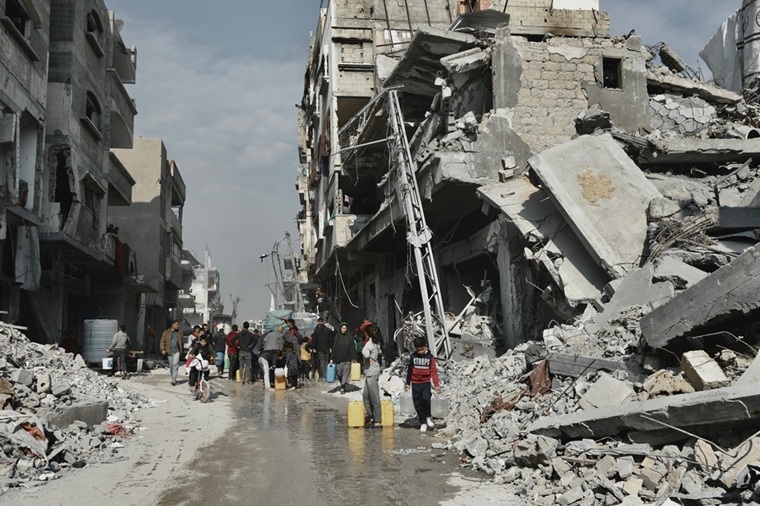 今にも倒壊しそうな建物に囲まれながら、給水に並ぶ人びと=2025年2月3日 © Nour Alsaqqa/MSF