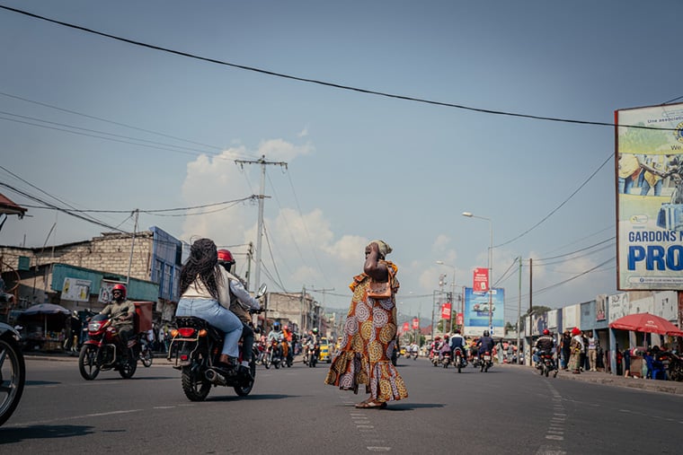 ゴマ市内にある総合病院の近くで道路を渡る女性=2025年6月27日 Ⓒ Jospin Mwisha