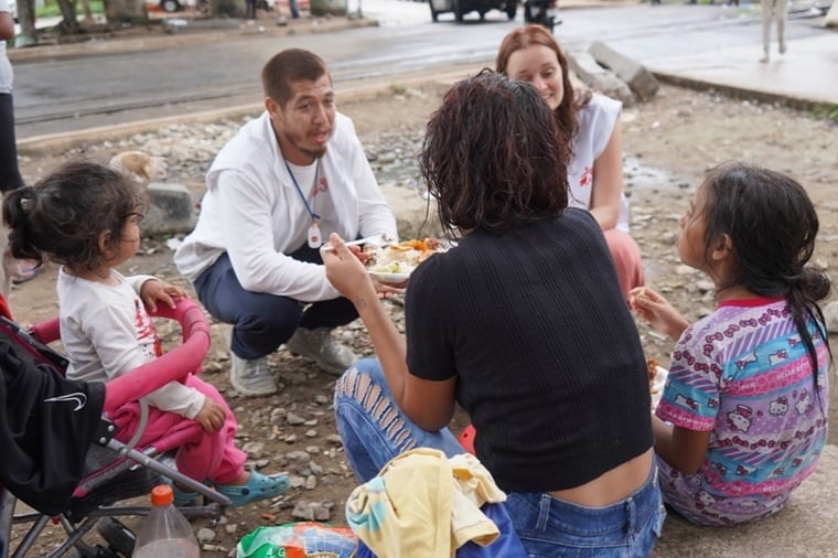 列車の乗車を待つ人たち(手前)に話を聞く国境なき医師団(MSF)の健康促進チーム=メキシコ南部コアツァコアルコスで2024年11月15日 Ⓒ Yotibel Moreno/MSF