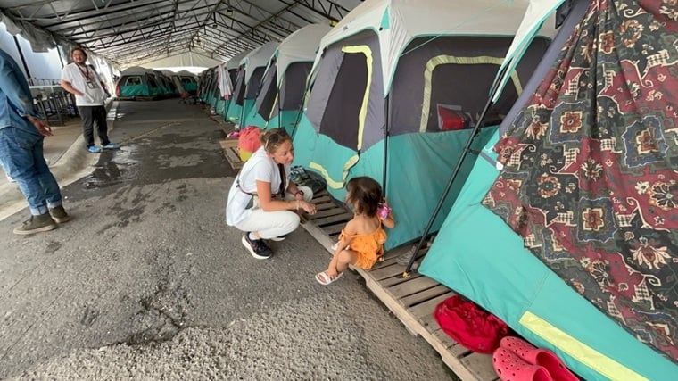 メキシコ北部の町マタモロスにある避難施設で子ども(中央右)と話すMSFのスタッフ。米国との国境に近いこの場所には、保護申請が未完了、または手続きを待っている150人以上が滞在している=2025年6月25日 Ⓒ Christian Zetina/MSF