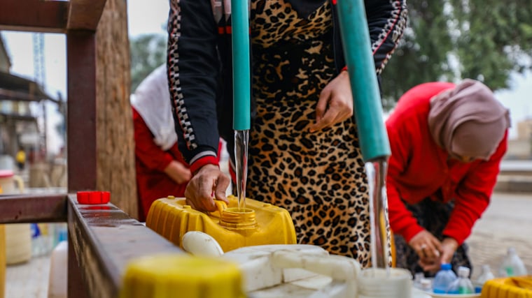 ハサカ市でNGOが設置した大型の赤い給水タンクから水をくむ女性たち＝2024年11月4日　Ⓒ Gihad Darwish／MSF