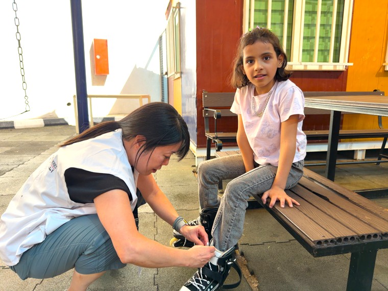 アンマンのMSF再建外科病院で遊んでいた子どもの患者（右）の靴ひもを結び直す中嶋＝2025年10月26日　Ⓒ MSF