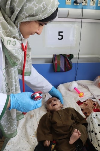 栄養失調の赤ちゃんを診察するMSFの医師　© Zahra Shoukat/MSF