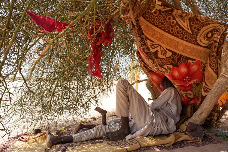 チャド：スーダン・北ダルフール州のザムザム・キャンプから避難してきたきょうだい、アイマンとアマニ。チャドのティネ一時滞在キャンプで、木の下に作った仮設避難所で遊ぶ＝2025年6月　© Julie David de Lossy/MSF