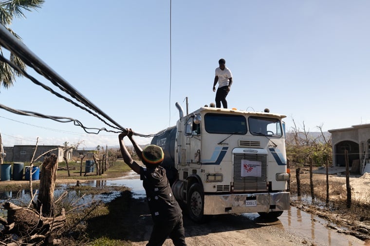 ジャマイカ／セント・エリザベス教区： MSFの給水車が通れるよう、住民が損傷した非電化の電線を脇へ押しやっている。MSFはハリケーン「メリッサ」による壊滅的な被害を受けた地域で対応にあたった＝2025年11月　© Georg Gassauer/MSF