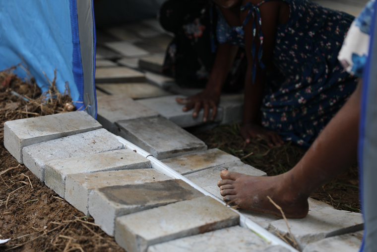 スリランカの仮設テントで避難生活を送る子どもたちが、住みやすくするために床にブロックを敷き詰めている＝2025年12月8日　© MSF
