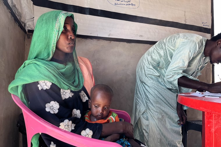 ブラ・クーカ村で、MSFの栄養失調プログラムに参加するザラ・アダムさん（左）と、重度の栄養失調に苦しむ生後9カ月の息子アダム・ムーサちゃん＝2025年11月5日　© Léa Gillabert/MSF