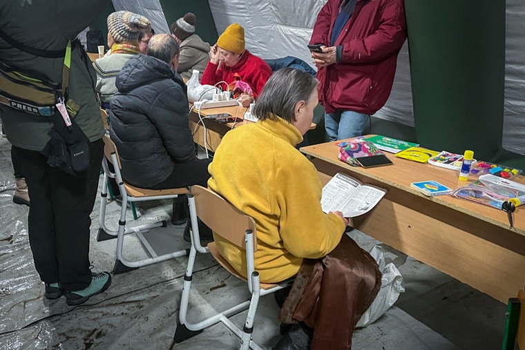 キーウに設置されたテント内で暖を取り、携帯電話の充電を待つ人びと＝2026年1月21日　© Anhelina Shchors/MSF