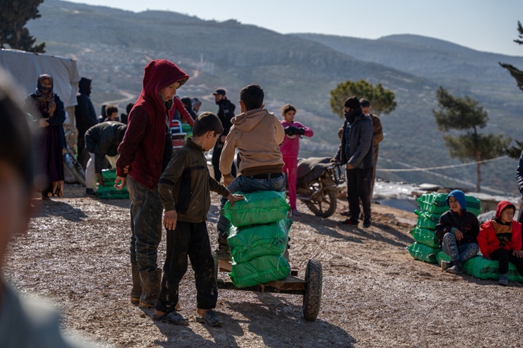 厳しい寒さの中、MSFから受け取った暖房用資材をテントまで運ぼうとする子どもたち。山の斜面に点在するテントまでは道が整備されておらず、運搬手段もないため、たどり着くのは容易ではない＝2026年1月20日　© Abdulrahman Sadeq/MSF
