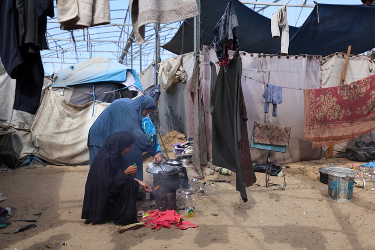ハンユニス郊外のマワシ地区にあるテントで、焚火をして食事を準備する母娘＝2025年10月9日　© Motasem Abu Aser/MSF