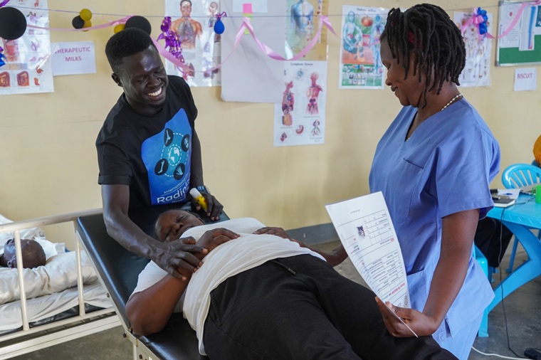 メンターの指導の下、患者の体の向きを変えるトレーニングを行う看護スタッフ（左）　© Alicia Gonzalez/MSF