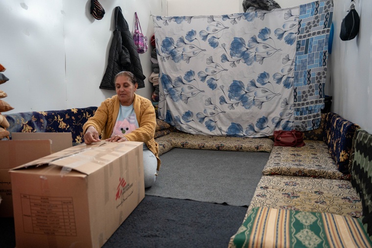 安全のため、自宅を離れざるを得なかった女性。避難先のシャハバでMSFから受け取った生活用品の箱を確認する＝2026年2月6日　© Asil Sari/MSF