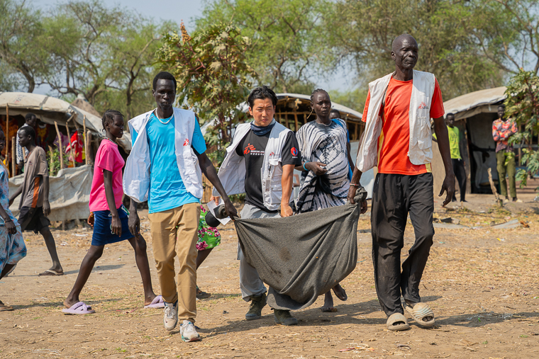 チュイルに向けて重傷患者（中央手前）を運ぶMSFスタッフたち＝2026年3月12日　© Isaac Buay/MSF
