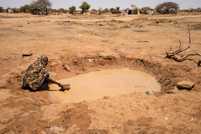 スーダンから逃れた人びとが暮らすチャドの難民キャンプで、水たまりから水をくむ女性。キャンプでは安全な水が圧倒的に不足している＝2025年6月15日　© Julie David de Lossy/MSF