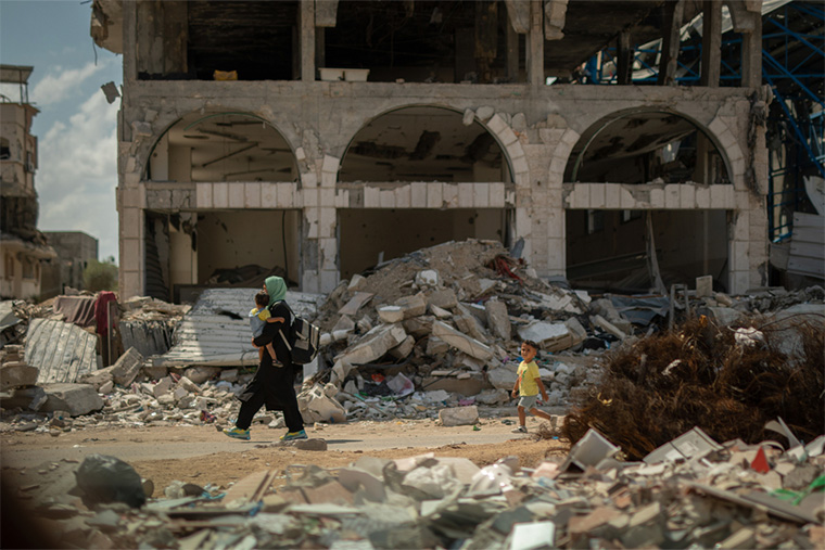 イスラエルの攻撃（こうげき）でこわされたガザの街を歩く親子　© MSF