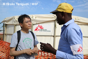 MSFの水タンクの前で、管理担当者から話を聞くいとうさん。ウガンダにて。
