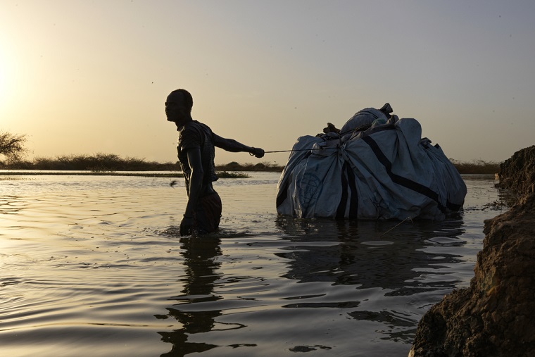 大規模な洪水が発生した南スーダン。被災した住民が荷物を運ぶ=2022年4月　© Peter Caton