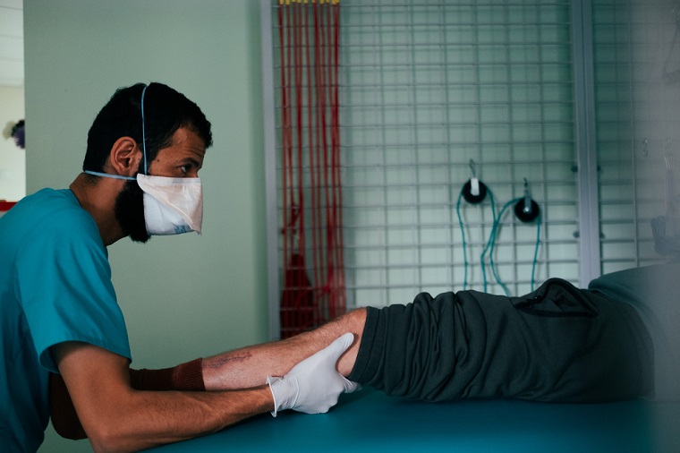 脚の手術を受けた患者にマッサージを施すMSFの理学療法士　© Hussein Amri/MSF 