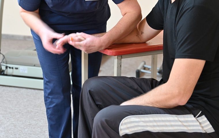 負傷した患者の手をマッサージする理学療法士。負傷者の増加に対して、理学療法士が不足している　© Joanna Keenan/MSF