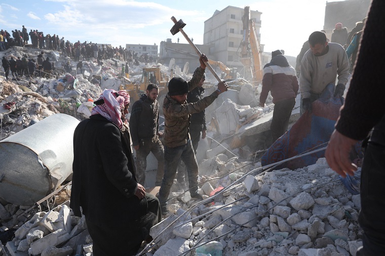 シリア北西部イドリブ県、地震で倒壊した建物のがれきの中で救助活動をする人びと＝2023年2月7日　© OMAR HAJ KADOUR 