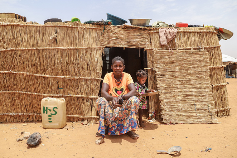 現在の住まいとなる簡易な小屋の前で、末娘と佇むサフィさん　Ⓒ MSF/Nisma Leboul
